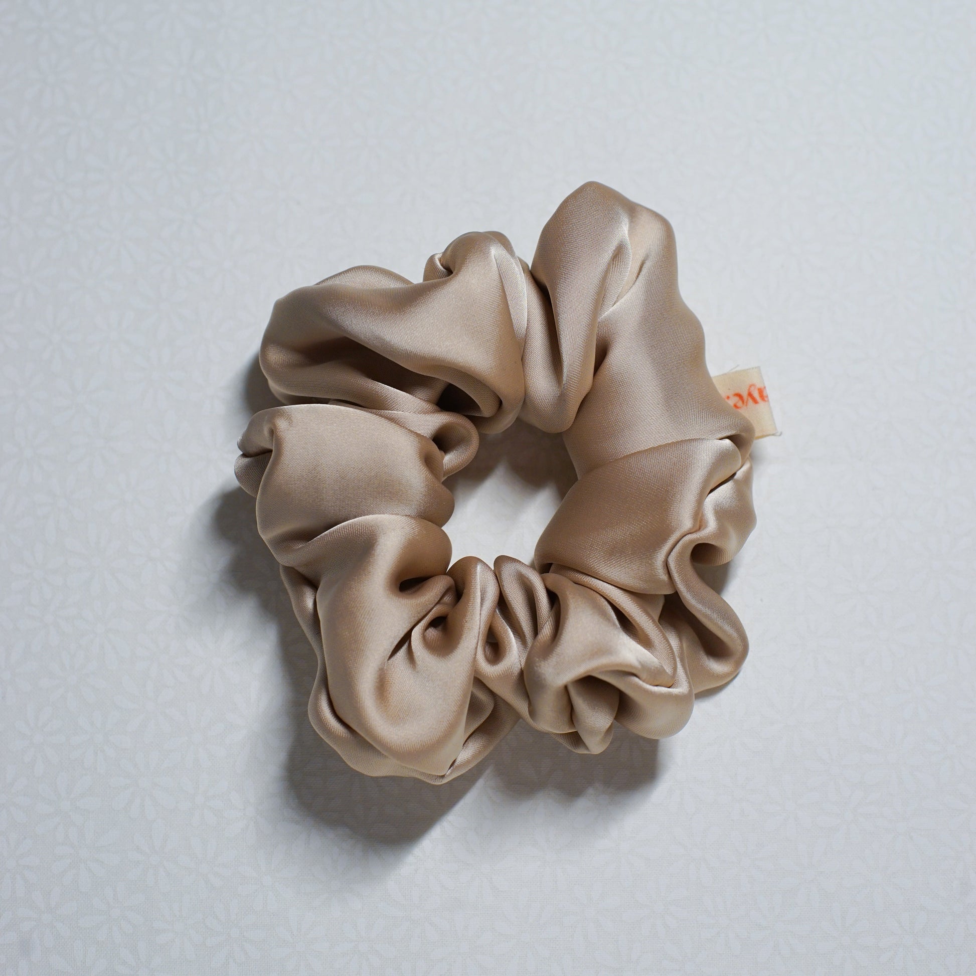 Beige scrunchie on a light gray background