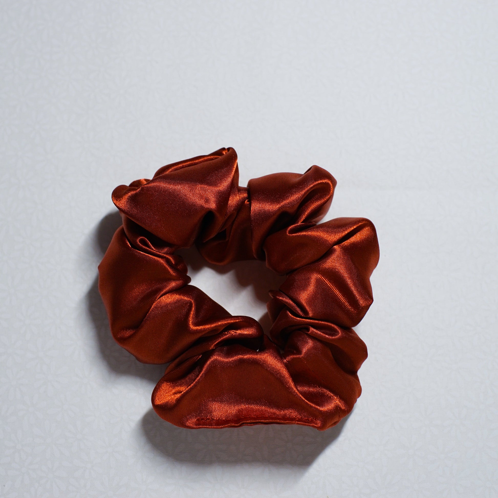 Red satin scrunchie on a light gray background