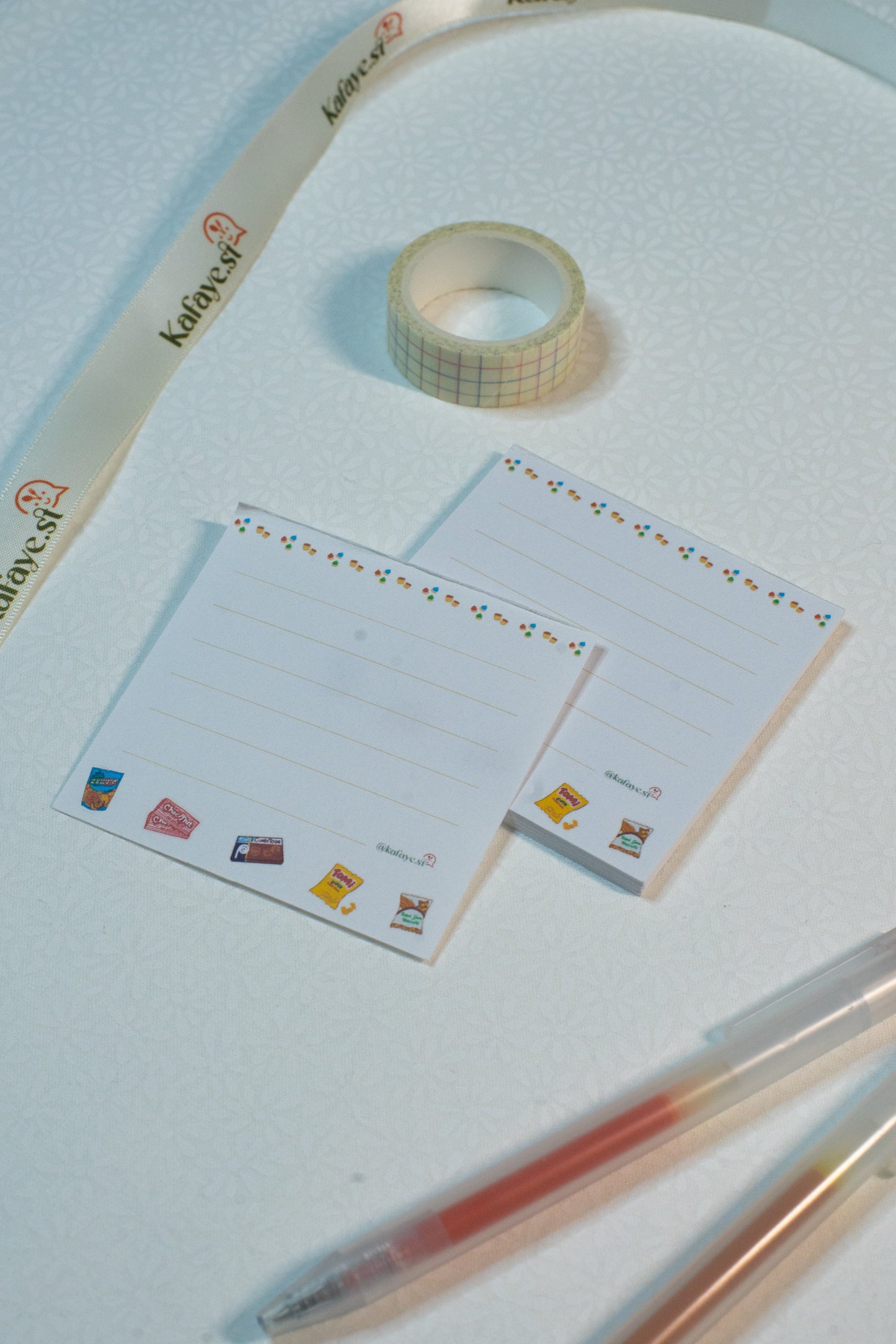 Roll of tape, stationery items, and pens on a light blue surface