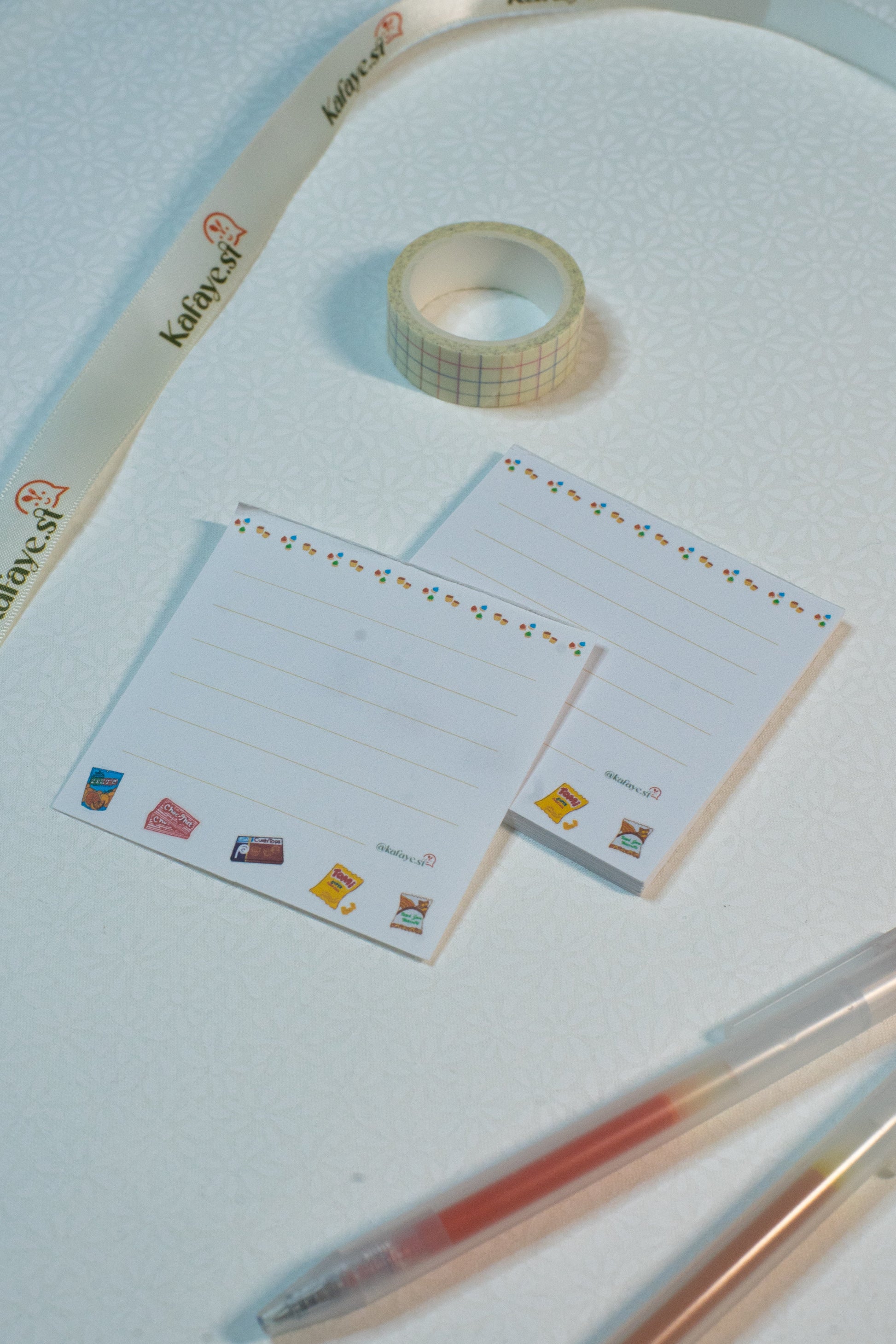 Roll of tape, stationery items, and pens on a light blue surface