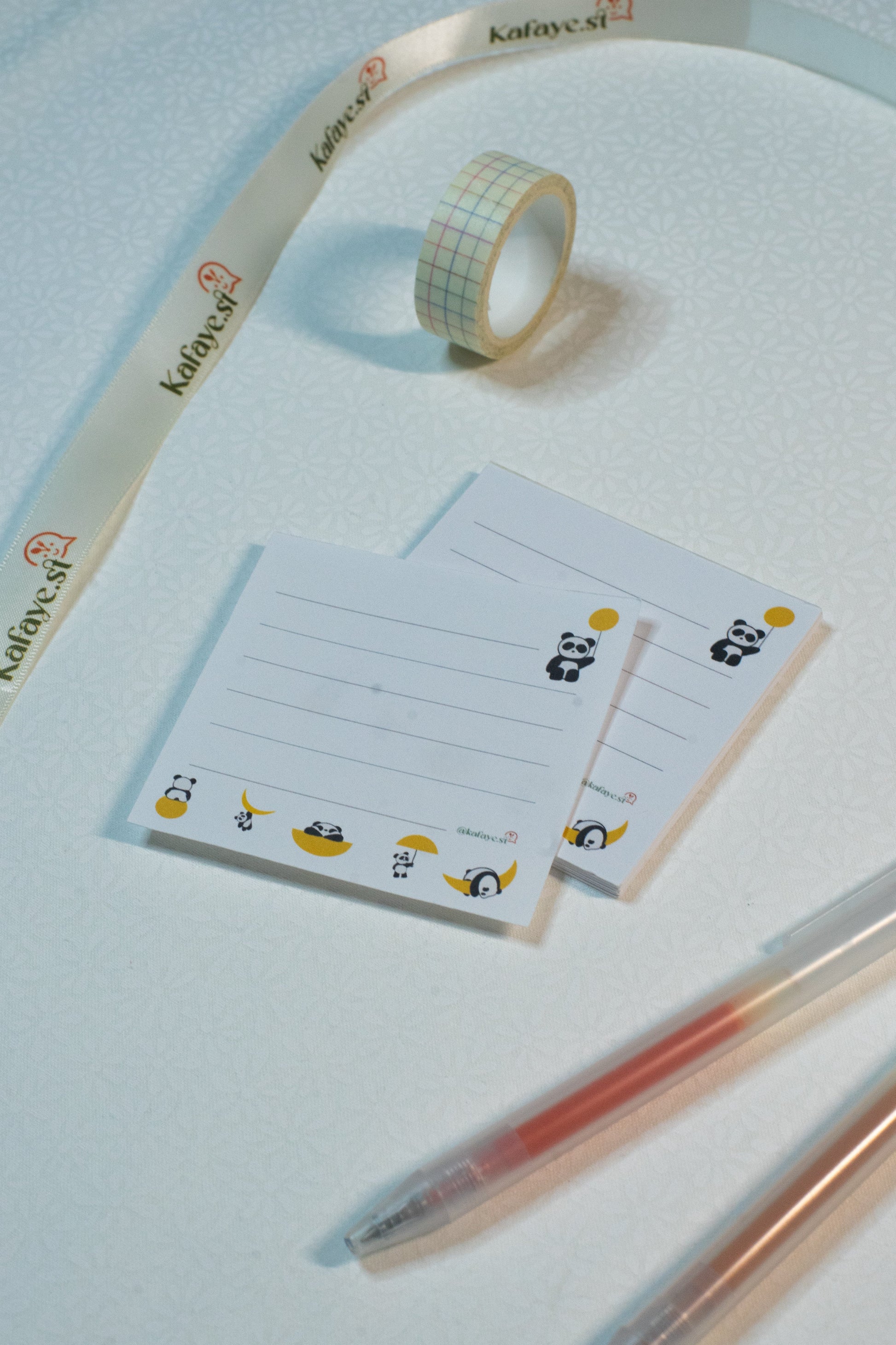 Notepad with panda illustrations, washi tape, and pens on a light blue background
